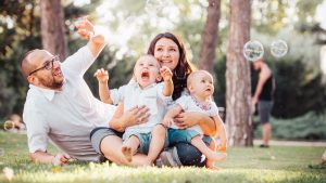 Joyful family enjoying a sunny day in the park while playing with bubbles.